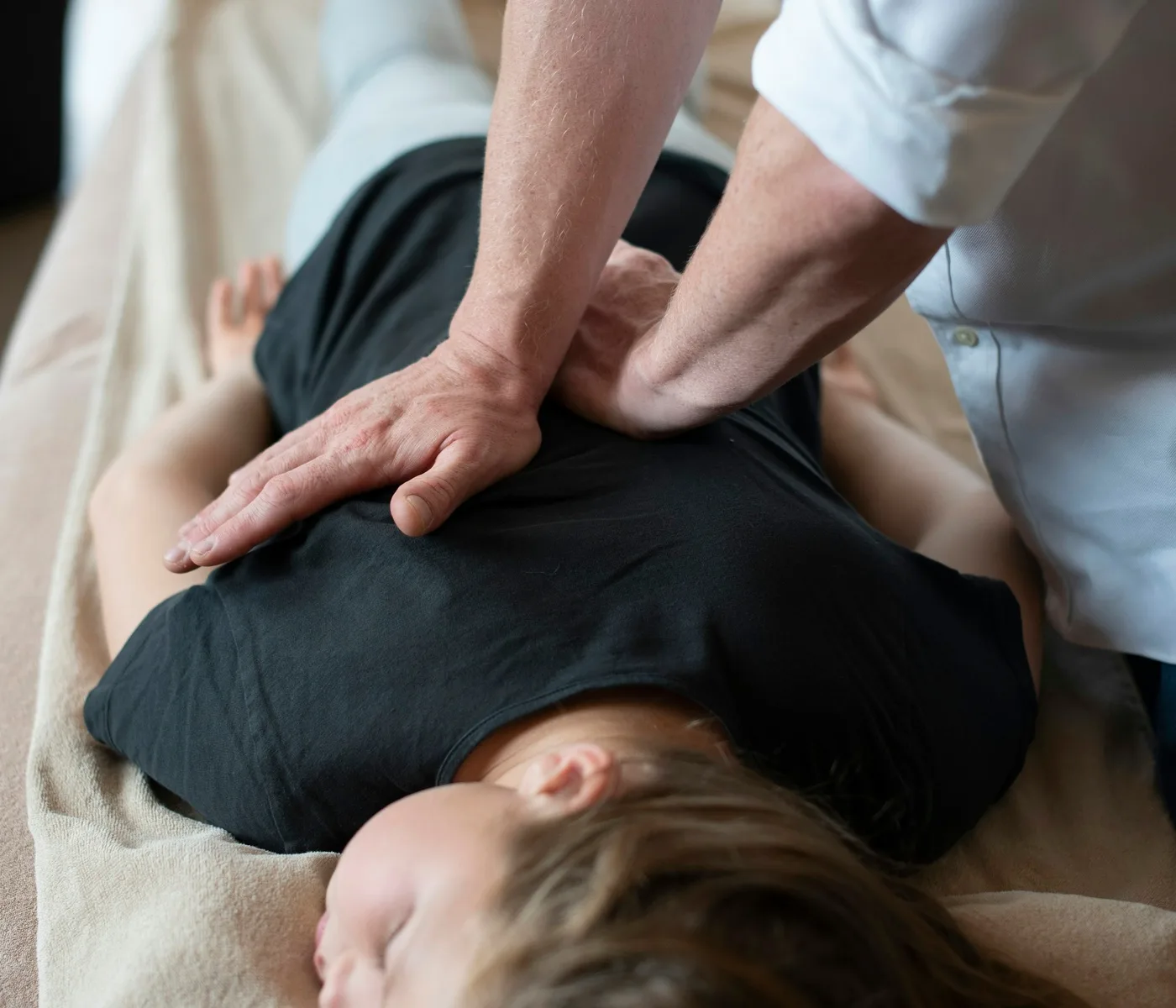 Osteopata che esegue un trattamento manuale su una paziente distesa e rilassata